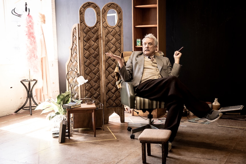 In a rehearsal room, furnished in a 70s style, Simon Burke, 64, sits, legs crossed, looking exasperated, a pen in one hand.