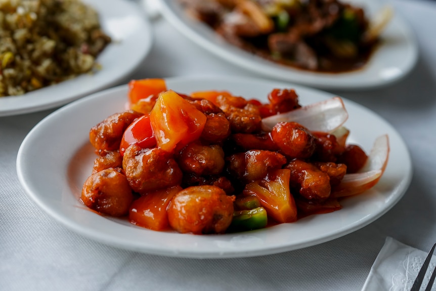 Plates of Chinese stir-fry dishes placed on top of a white table.