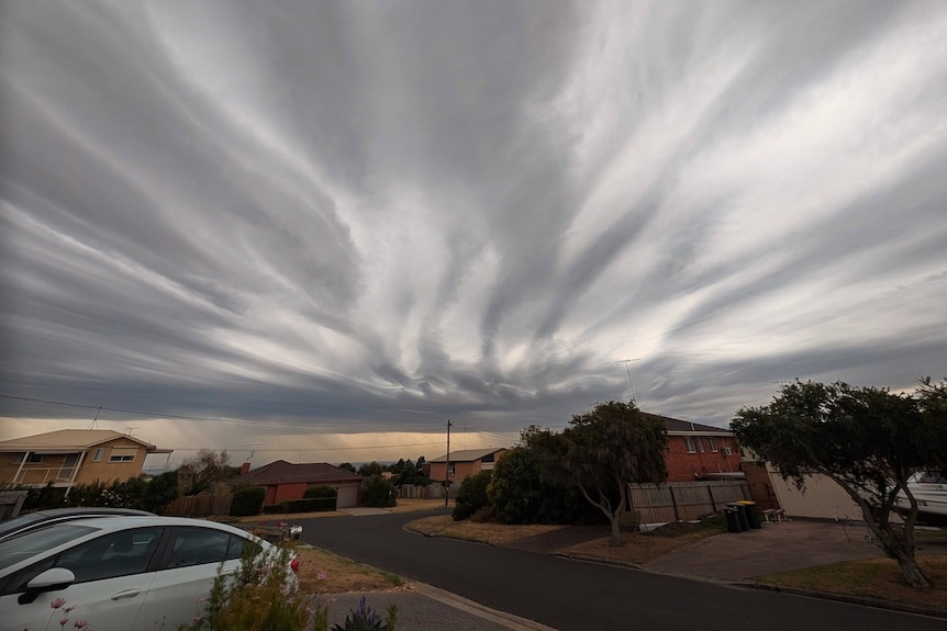 White and grey clouds streaked in the sky above brick houses.