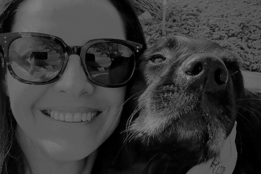 A woman wears a pair of sunglasses with her pet dog