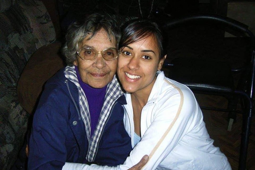 Two woman sit and smile at the camera.