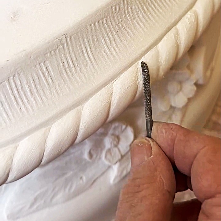 Close-up of sculptor working on detail of artwork.