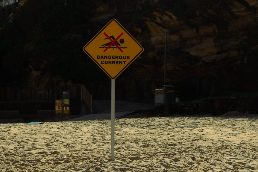 A sign on the beach that saus dangerous currents.
