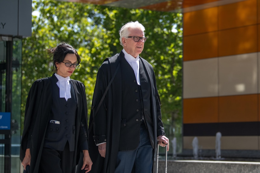A man and woman in robes walking out of a court.