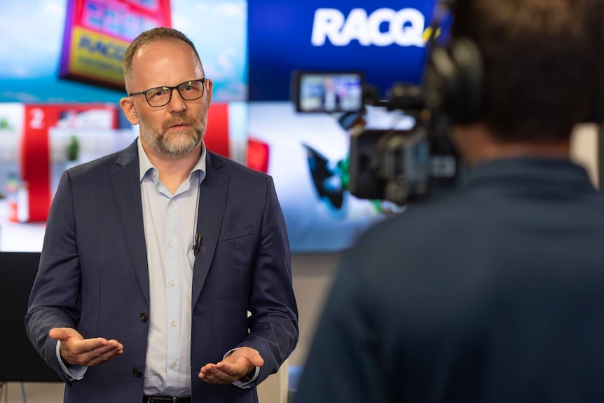 A man with glasses and a beard is interviewed on camera
