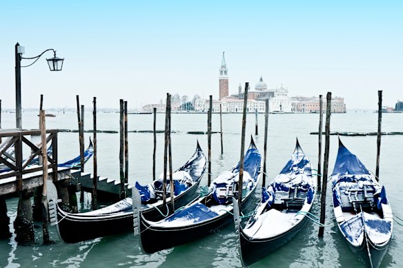 Snow-covered gondolas moored near St Mark’s Square in a wintry Venice, Italy.