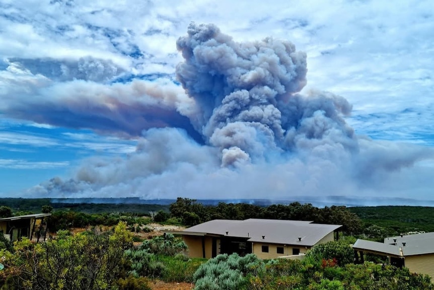 A photo of the south west landscape with a house in foreground and a huge smoke plume in the background