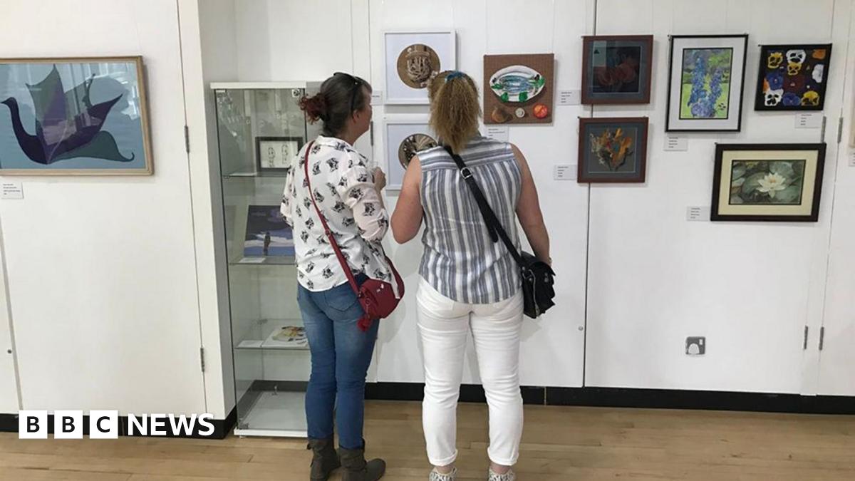 Two women stand in front of a selection of artworks mounted on the white walls of Goole Museum gallery