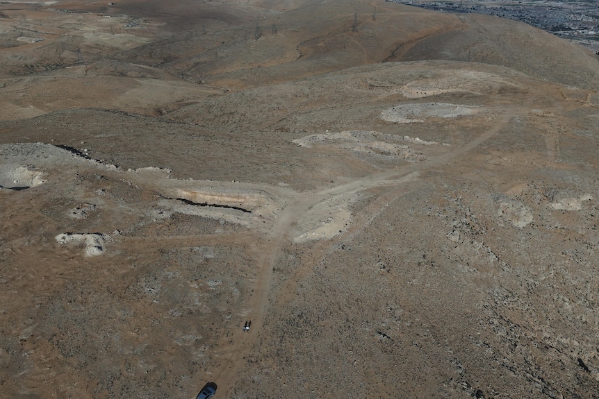 Aerial view of a mass grave in a vast landscape. 