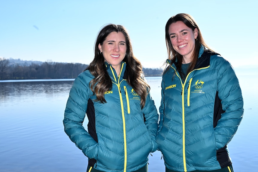Bobsliegh competitors Bree Walker and Kiara Reddingius posing for a promotional photograph in front of a lake, wearing jackets