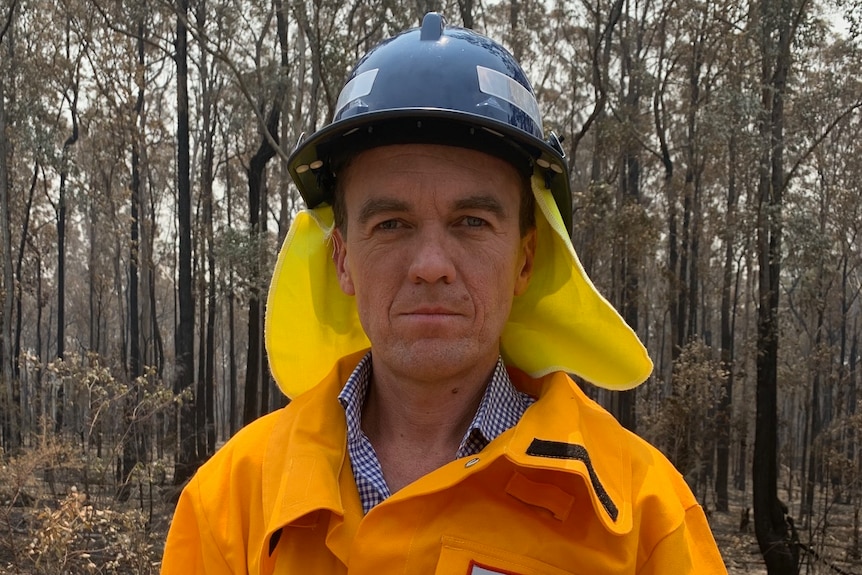 Michael Rowland stands on a fire ground in high visibility media-branded protective clothing 