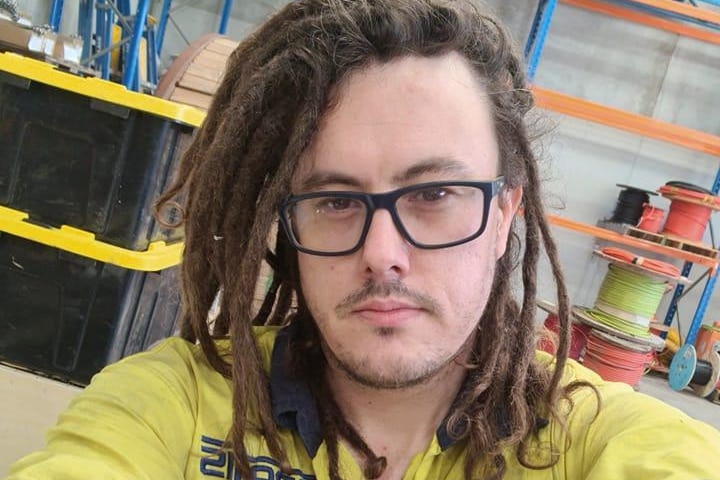 A selfie of a man wearing a pair of glasses with lock braids and in hi-vi uniform