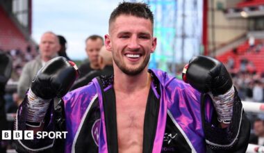 Rhys Edwards holds up his gloves in an outdoor ring