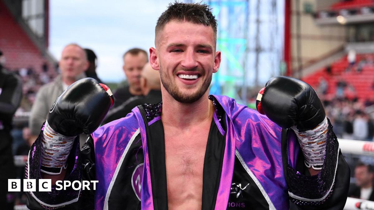 Rhys Edwards holds up his gloves in an outdoor ring