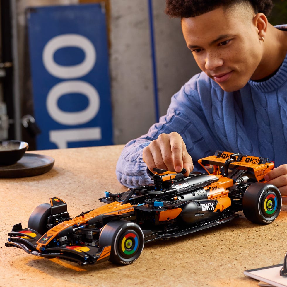 detailed model of a race car on a table with a person adjusting it