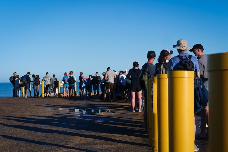 Tourists line the boat ramp awaiting a tender out to Ningaloo Reef tour boats.