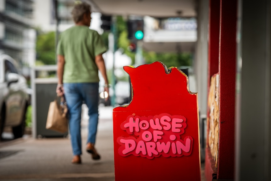 A board bearing the name "House of Darwin" stands in front of a shop on a street.