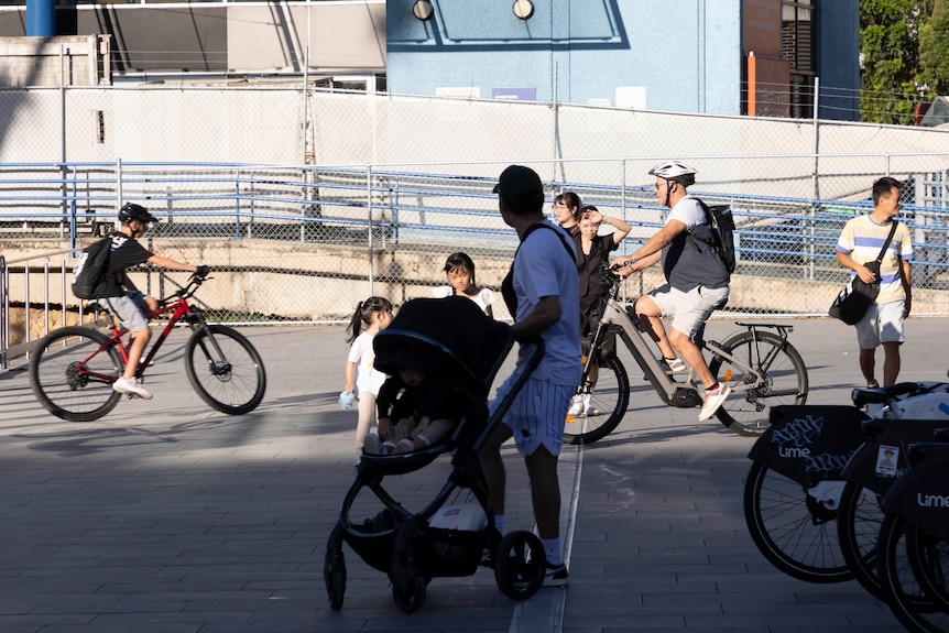 cyclists ride between pedestrians on a wide pathway