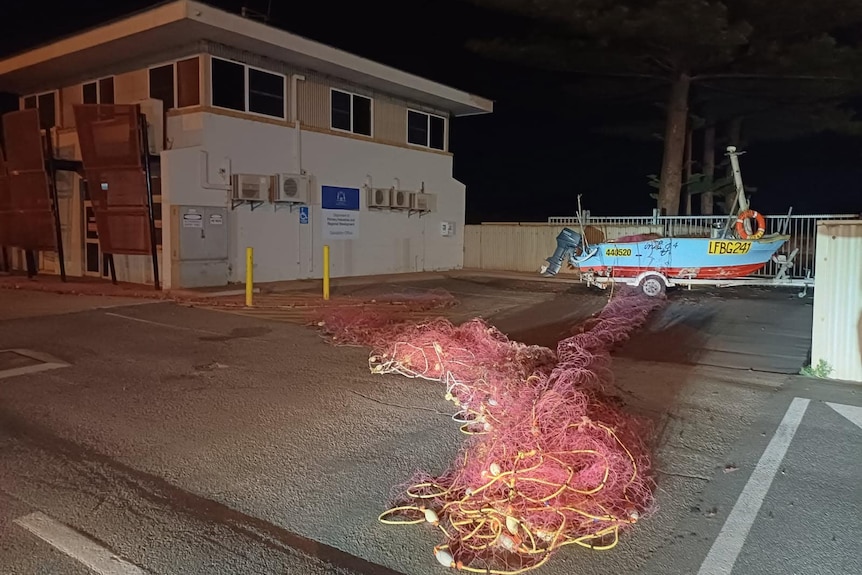 A boat chained to a fence, taken at night
