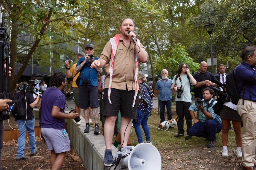 Protest organiser Josh Lees addresses a crow outside Surry Hills Police Station.