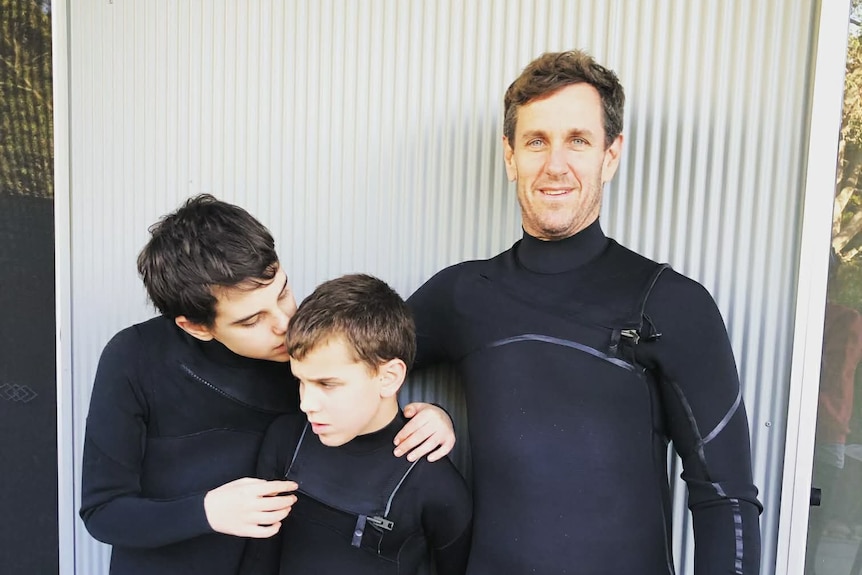Two teenage boys and their father, all in wet suit. 