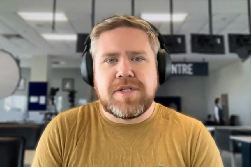 A man wearing a yellow jumper and black headphones