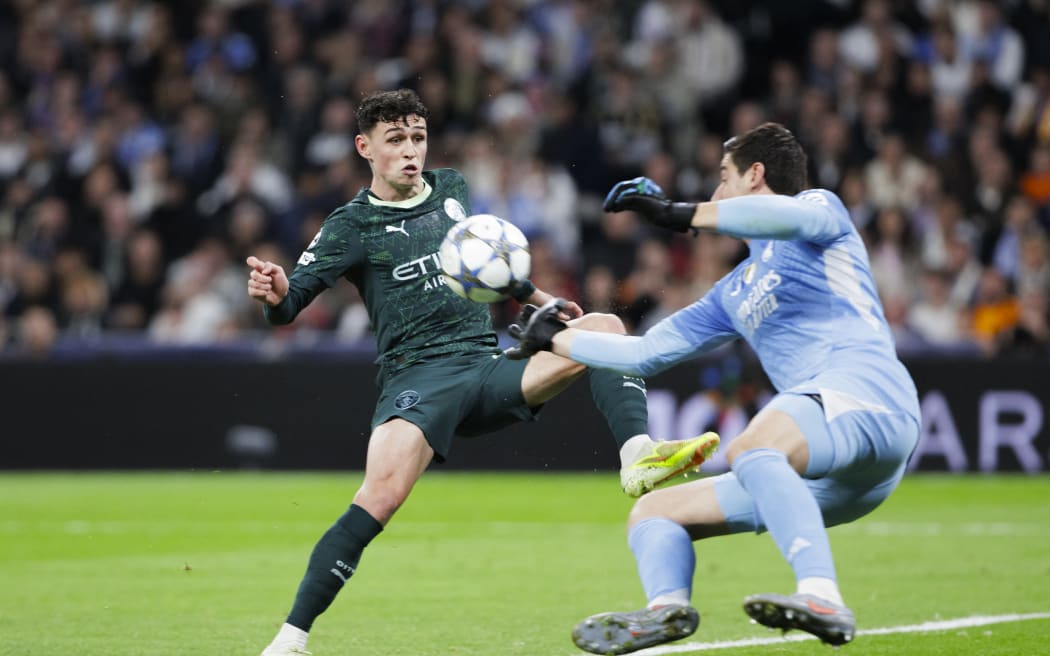 Thibaut Courtois of Real Madrid (R) and Phil Foden of Manchester City in action during a 2025 Champions League match.