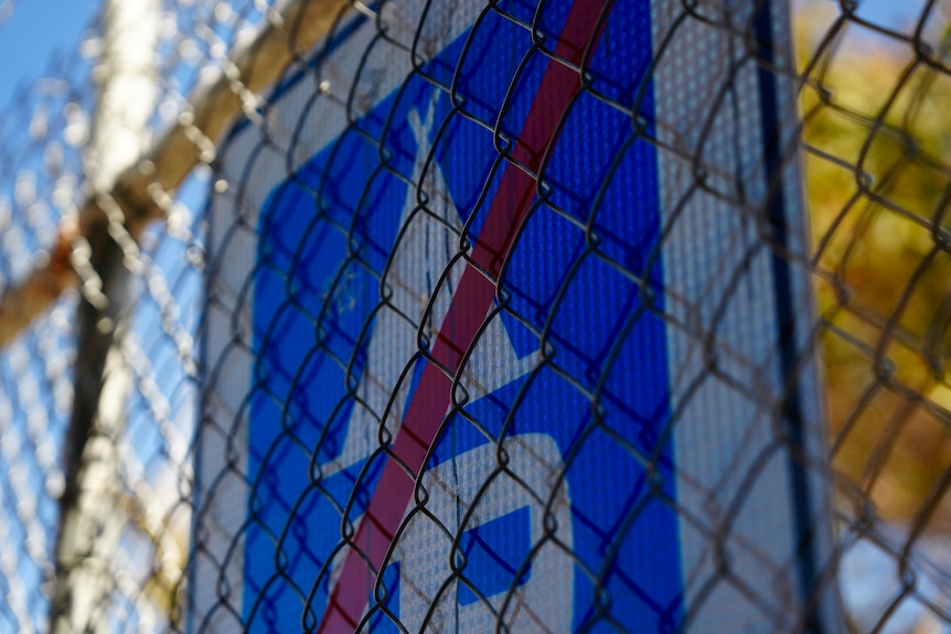 A no camping sign attached to a metal fence.
