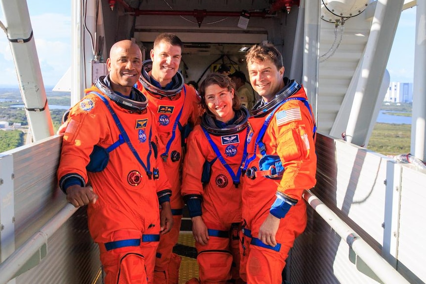Victor Glover, Jeremy Hansen, Christina Koch and Reid Wiseman in orange flight suits. 