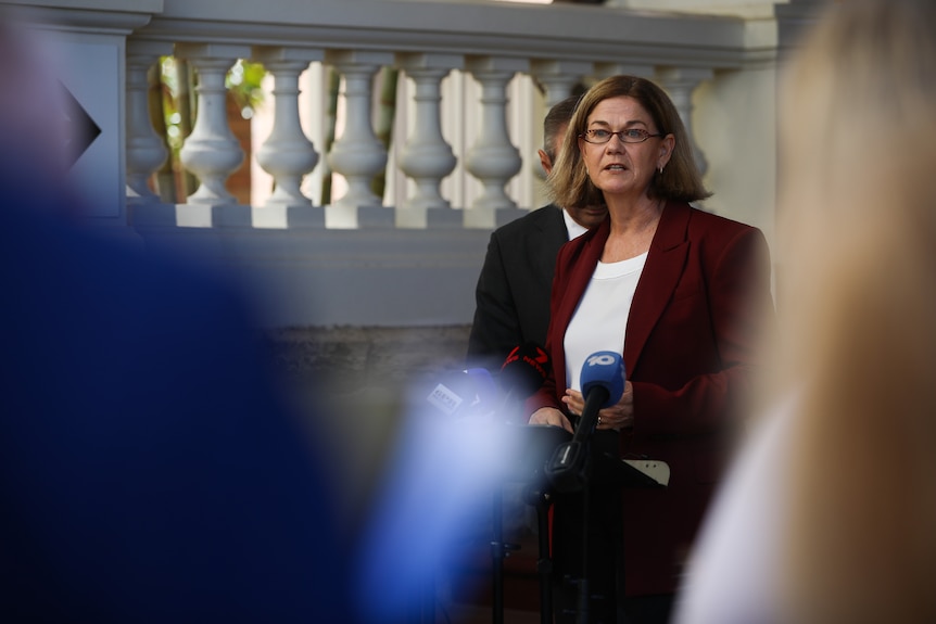 Meredith Hammat delivers a press conference wearing a maroon jacket and white top