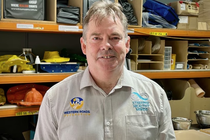 A medium of man in front of a shelf.