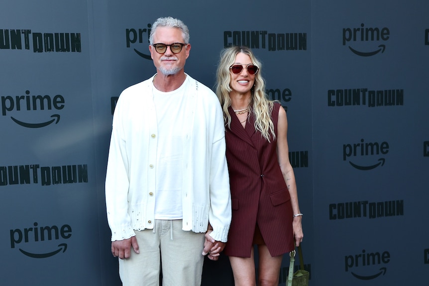 A man and a woman standing together holding hands.