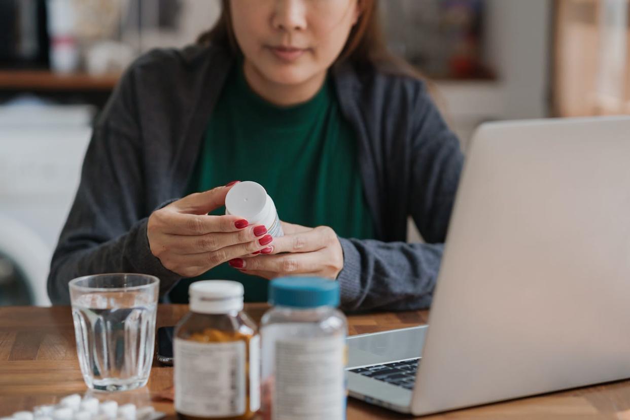 close up of asian female patient reading a medicine or dietary supplement label such as vitamins, making the body strong, symptoms of illness at home.