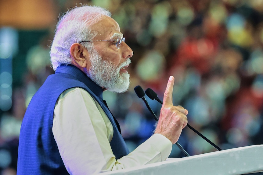 Narendra Modi gestures with his finger while speaking at a lectern