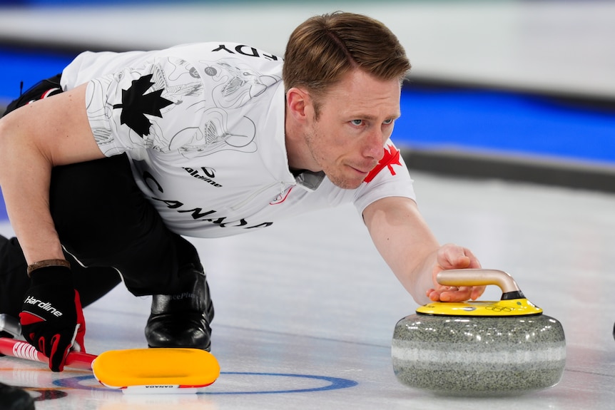 A curler with short brown hair is mid-game
