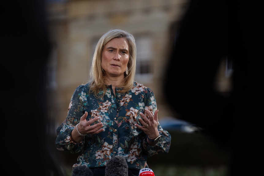 Woman with blonde hair speaks on a green lawn