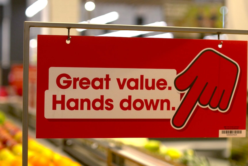 A red and white sign hangs over displays of fruit in a Coles supermarket and reads "great value, hands down"