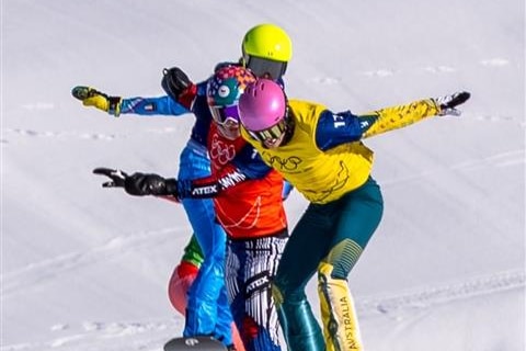 Snotboard cross competitors racing over a jump