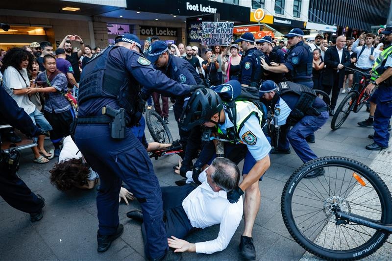 Police around a male protester on the ground.