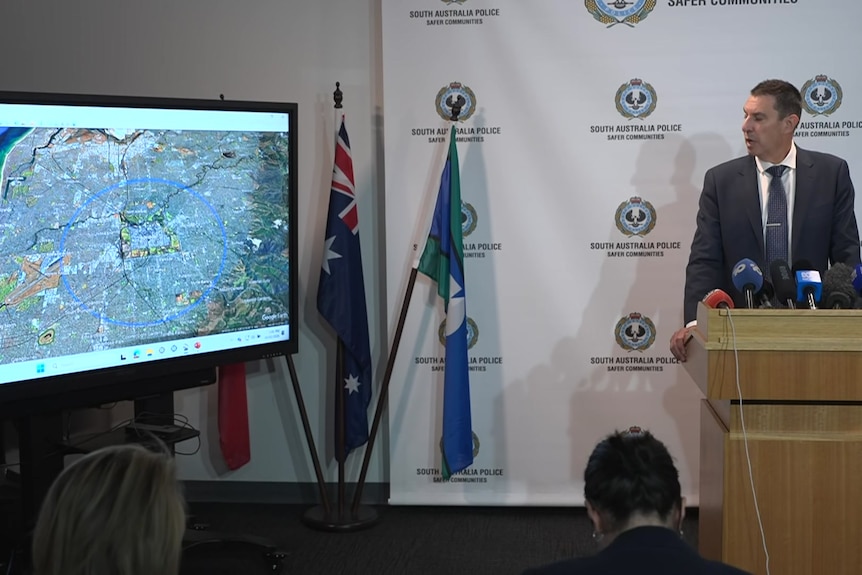 A man wearing a suit and tie looking at a screen with a map on it