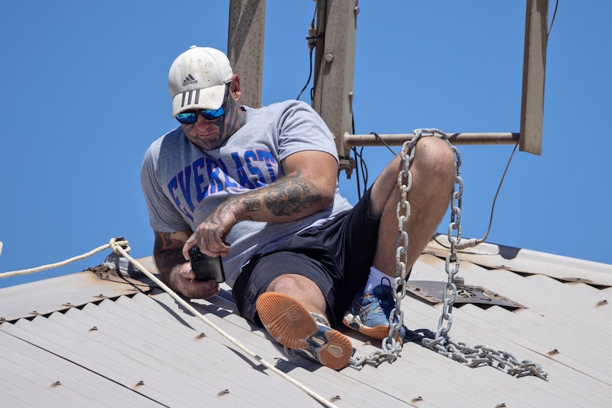 John Higham chained to the roof of the DPIRD building in Geraldton.