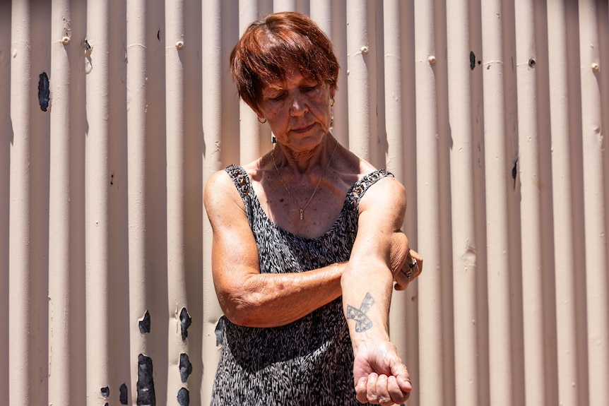 A woman showing her tattoo on left arm.  