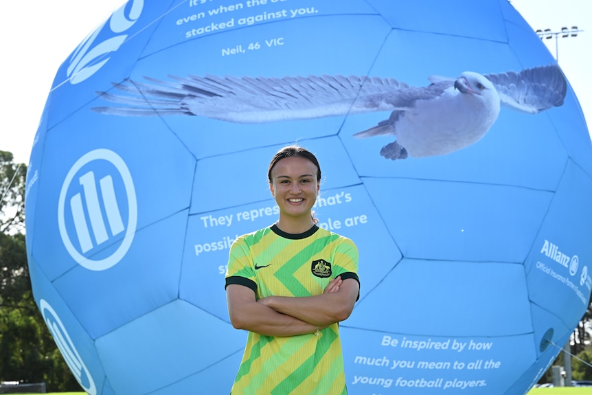 A female soccer player standing in front of a marketing banner.