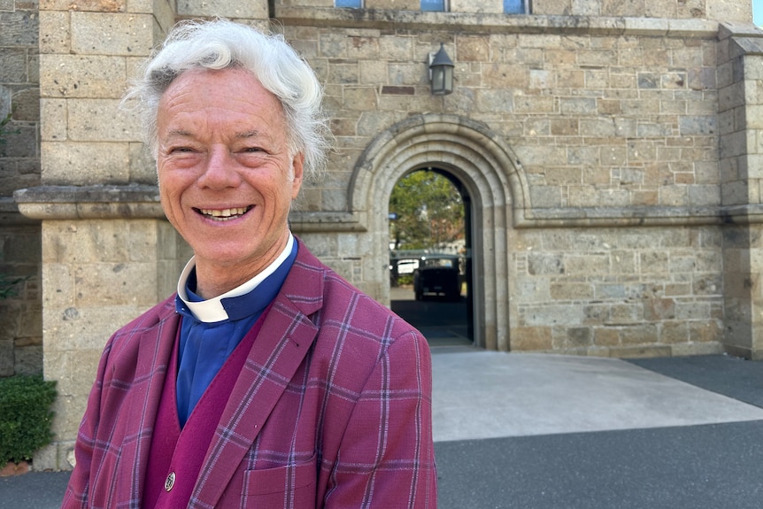 a priest in a purple suit outside a church
