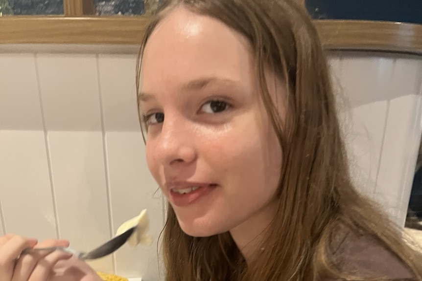 Teenage girl eating food with spoon