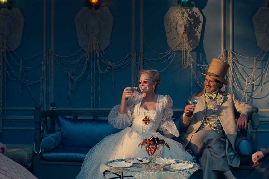 A man and a woman in victorian clothes drink tea