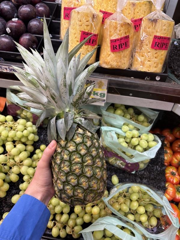 A picture of a pineapple infront of a fruit stand.