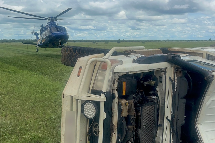 Helicopter landing near four-wheel-drive on its side