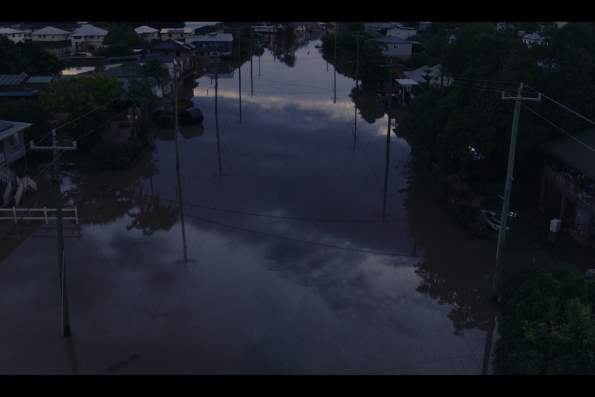 The flooded town of Lismore at twilight, with houses submerged up to their lower levels and reflected in the floodwaters.