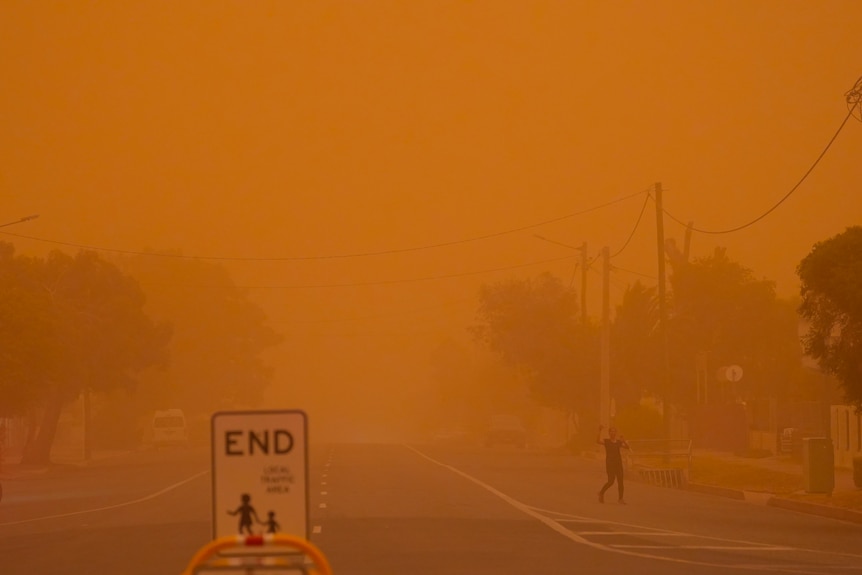 A woman crosses the road during a dust storm in Broken Hill